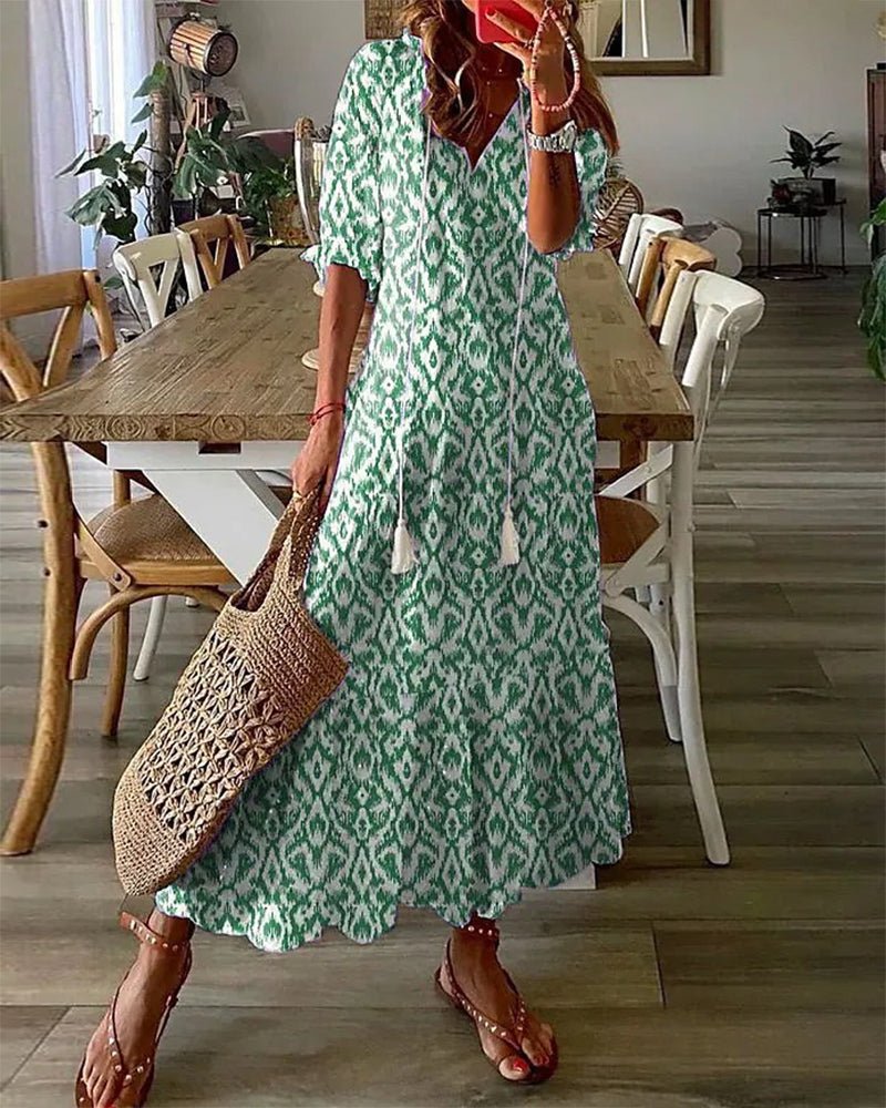 A woman wearing the Margaret boho midi dress with tassel ties at the neckline and a ruffled skirt.