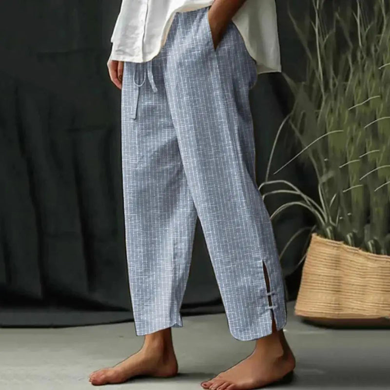 Woman wearing tapered drawcord-waist pants with sandals, standing in a sunlit garden.