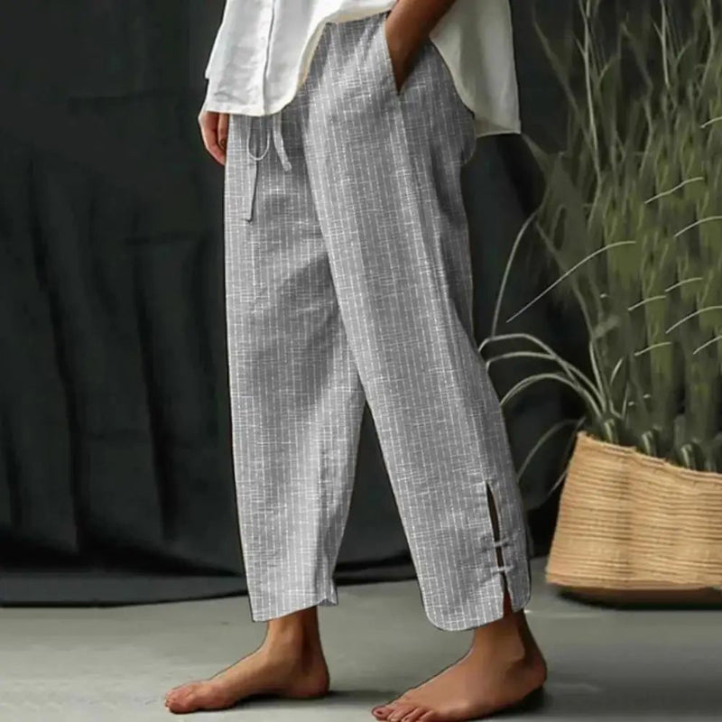 Woman wearing tapered drawcord-waist pants with sandals, standing in a sunlit garden.