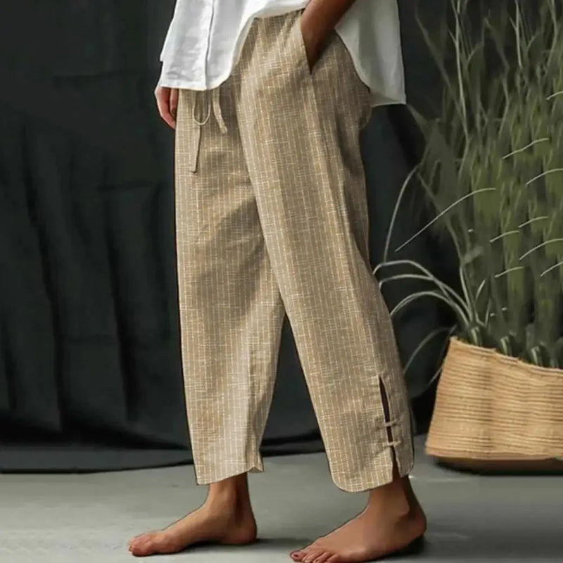 Woman wearing tapered drawcord-waist pants with sandals, standing in a sunlit garden.