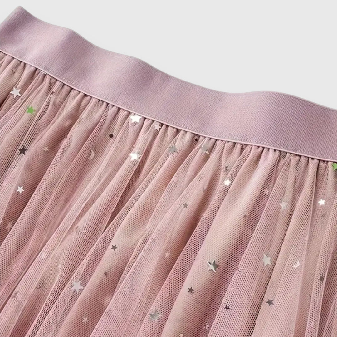 A woman wearing a high-waisted shimmering skirt with a soft ruffled hem.