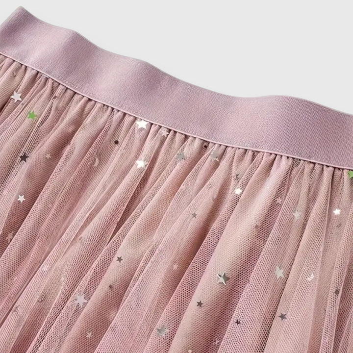 A woman wearing a high-waisted shimmering skirt with a soft ruffled hem.