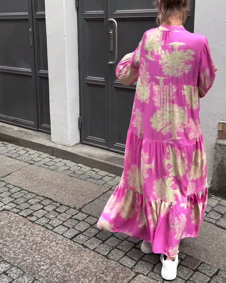Woman wearing the Sylvie flowing maxi dress with a delicate print and V-neckline, the skirt moving softly as she walks.