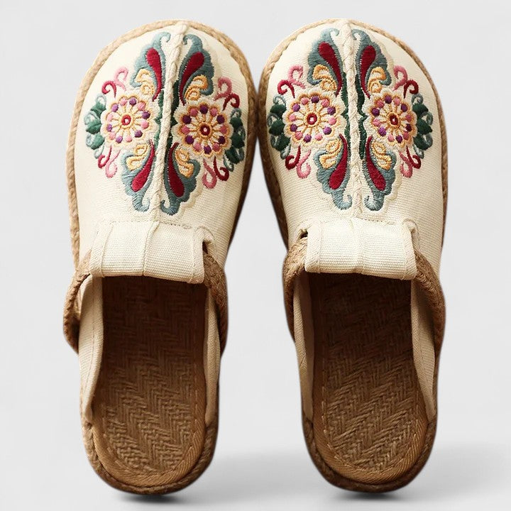 A woman wearing softly embroidered flat sandals, walking with ease on a sunny day.