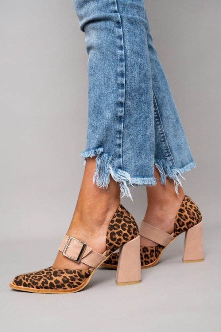 A woman wearing leopard-print pointed heels with a neutral buckled strap and block heel, stepping out in a polished outfit.