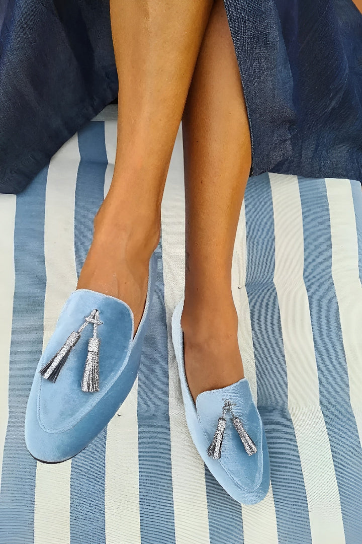A woman wearing blue slip-on loafers with a soft finish, styled for a relaxed day out.