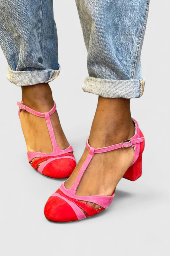 A woman wearing berry red heels with an ankle strap, stepping out in a confident evening look.