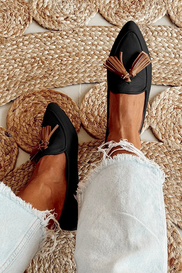A woman wearing modern slip-on loafers with playful fringing, styled for an easy day in town.