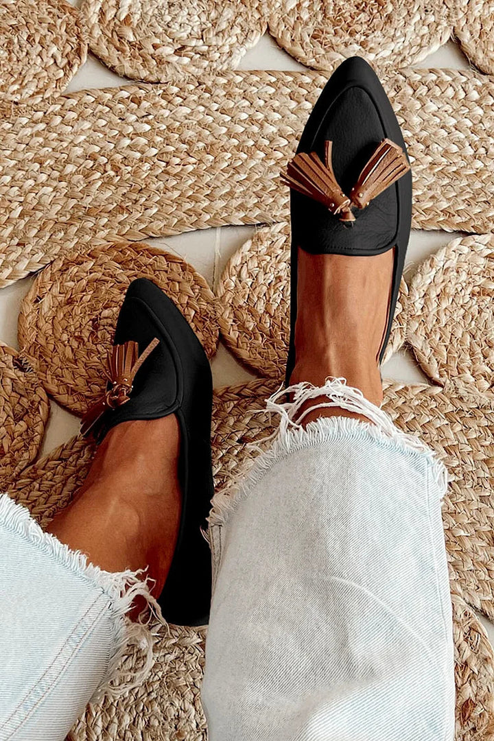 A woman wearing modern slip-on loafers with playful fringing, styled for an easy day in town.