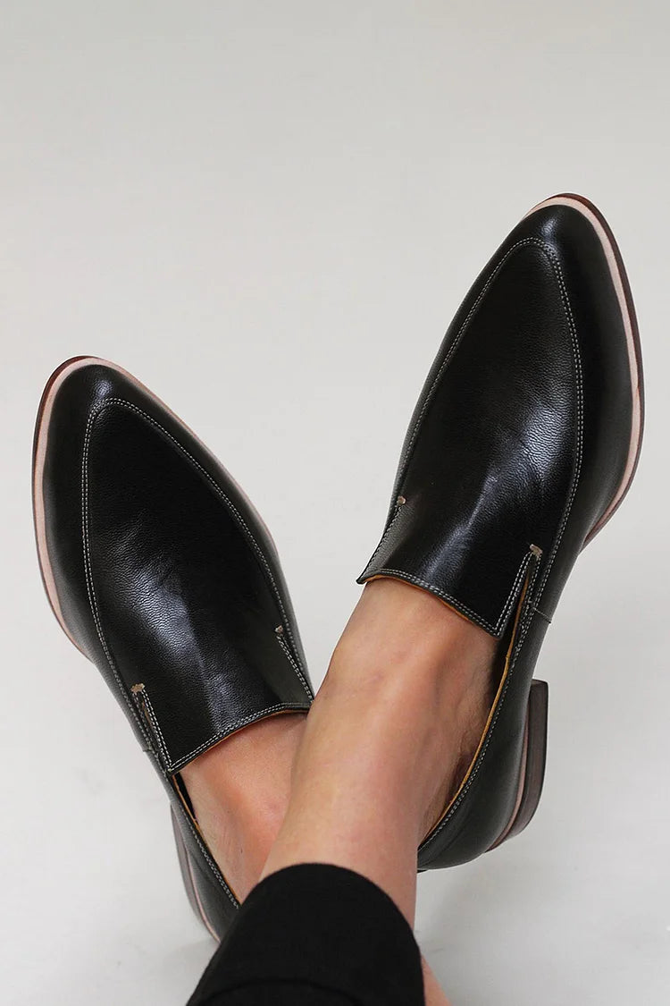 A woman wearing black patchwork slip-on loafers, styled for an easy day in the city.