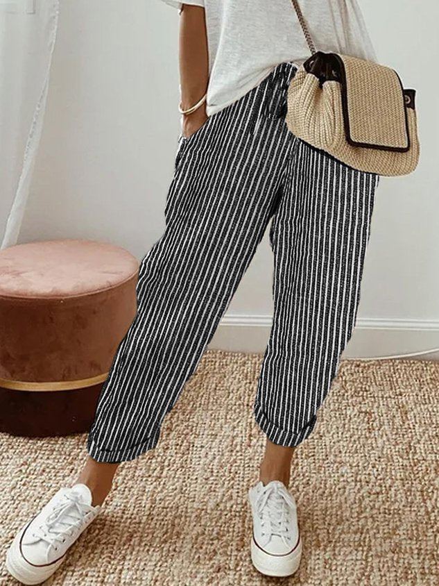 A woman wearing flowing elegant pants with a soft elastic waist and deep pockets.