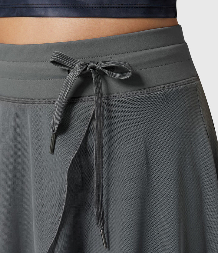 A woman in an elegant high-waisted flowing skirt, styled for a versatile day-to-evening look.