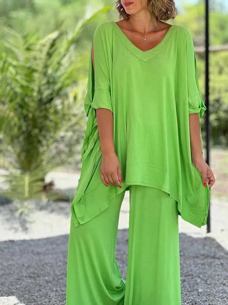 A woman wearing a draped top with shoulder cut-out details and matching wide pants.