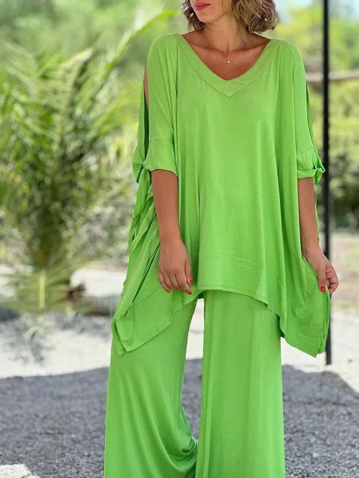 A woman wearing a draped top with shoulder cut-out details and matching wide pants.