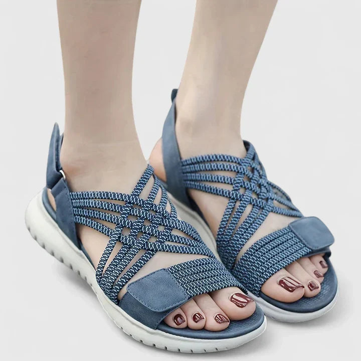 Blue open-toe sandals with woven stretch straps and a broad, cushioned white sole.