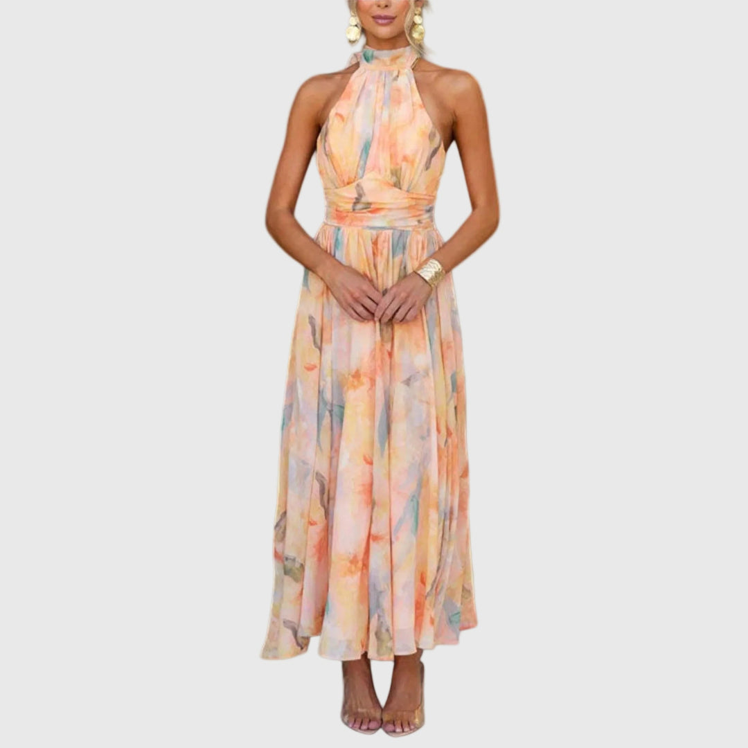 Woman wearing the Carol halterneck maxi dress in warm watercolour tones at an outdoor celebration.