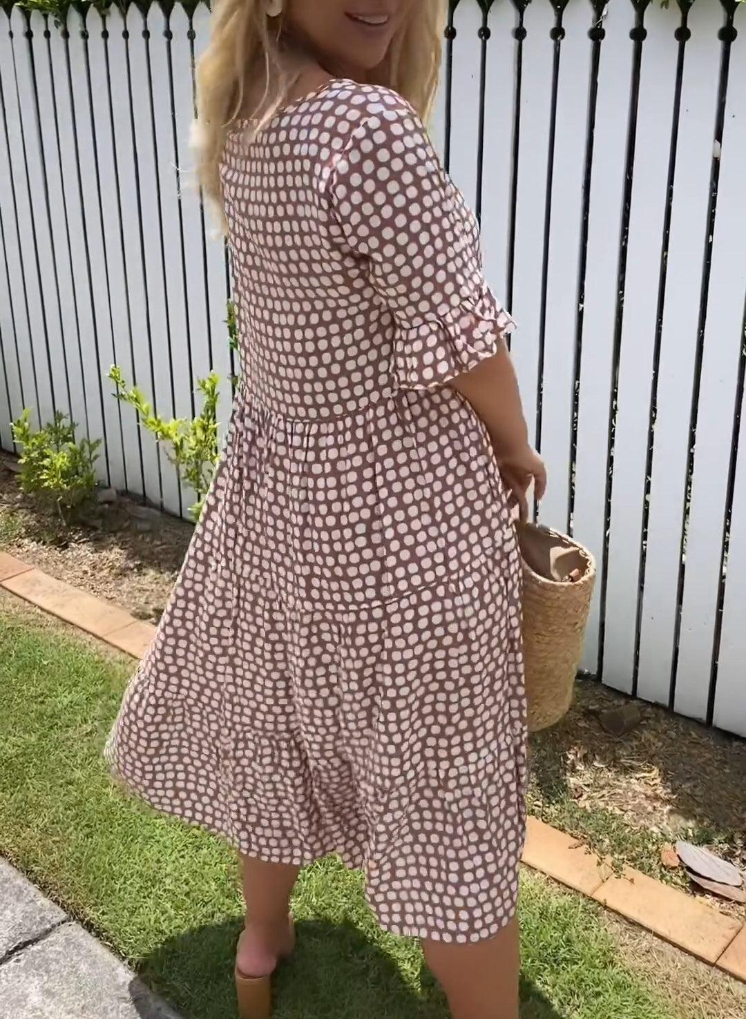 Woman wearing the Natalie™ polka dot midi dress with short sleeves, relaxed and smiling in a summer setting.
