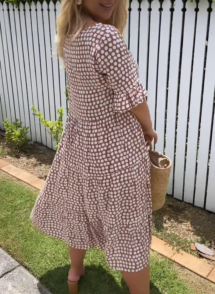 Woman wearing the Natalie™ polka dot midi dress with short sleeves, relaxed and smiling in a summer setting.