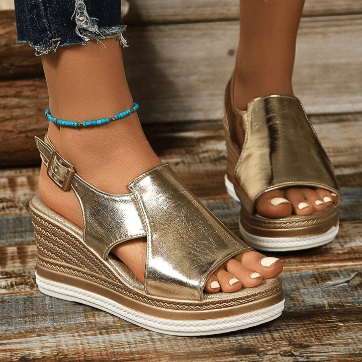 A woman wearing gold metallic sandals with a cushioned insole and wide, supportive fit.
