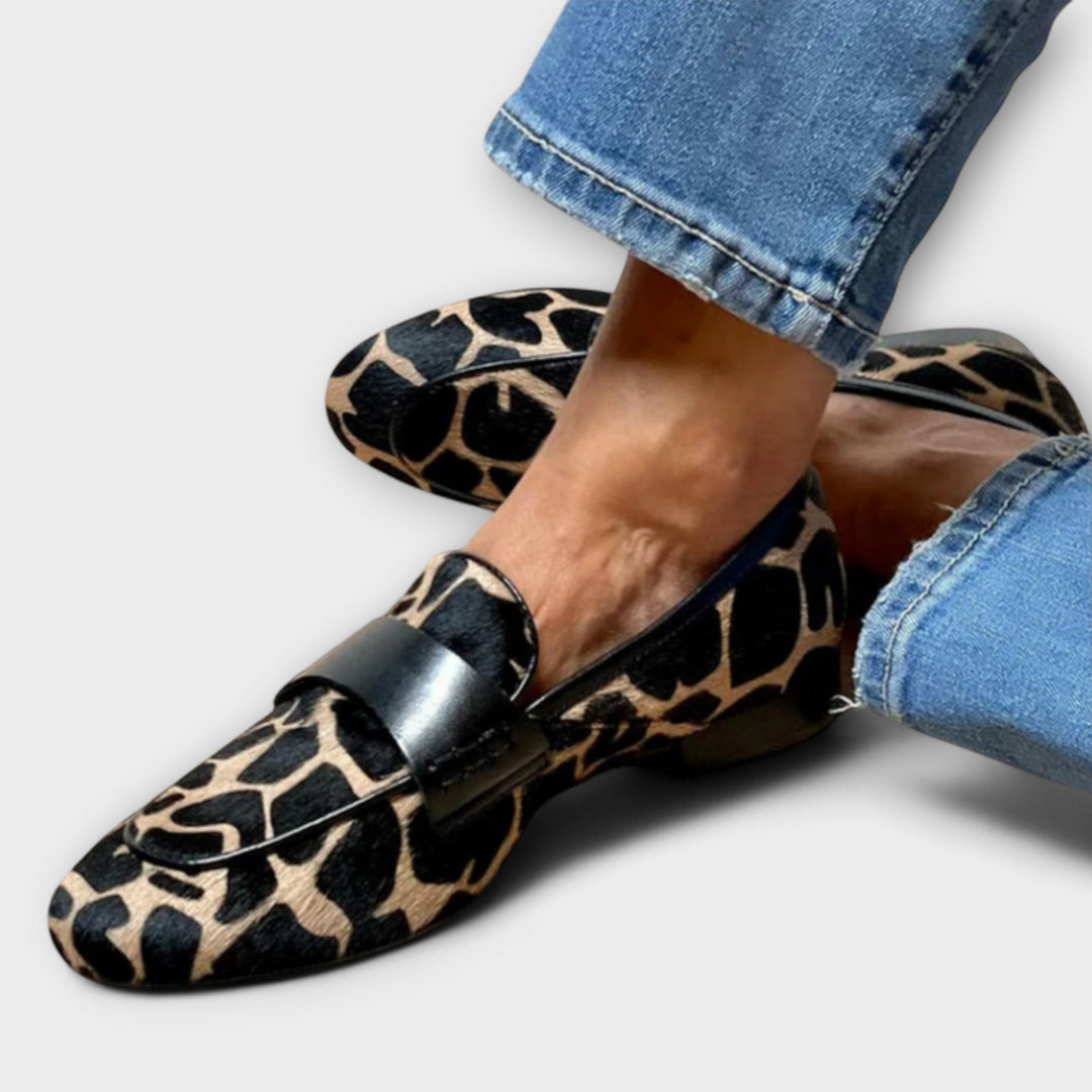 A woman in leopard-print loafers stepping out on a city pavement.