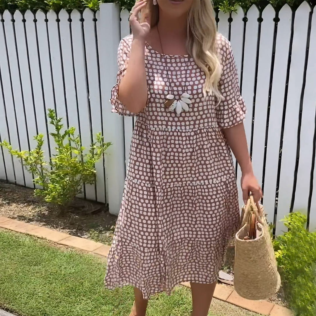 Woman wearing the Natalie™ polka dot midi dress with short sleeves, relaxed and smiling in a summer setting.