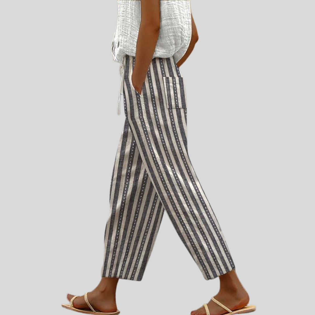 A woman wearing navy-and-cream vertical striped pants with an elastic waist and side pocket.
