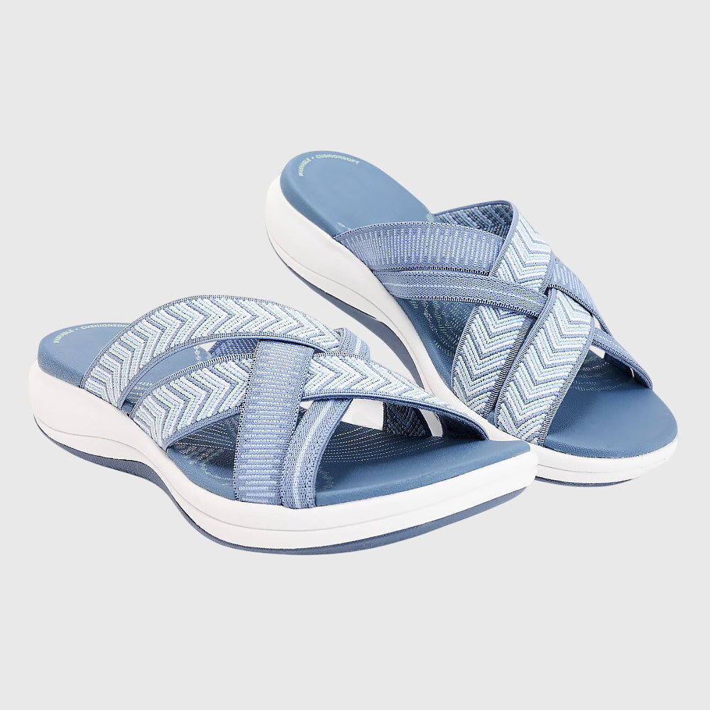 A woman in beige lightweight soft sandals walking easily on a sunny path, feet cushioned and supported.