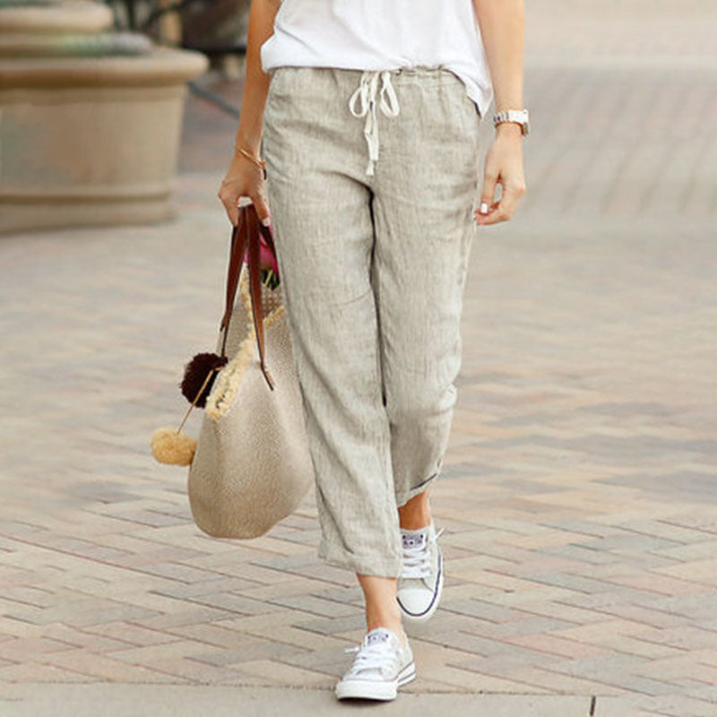Woman wearing flared drawcord-waist pants with sneakers, walking through town.