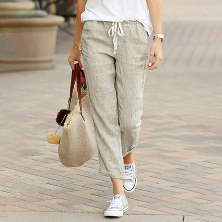 Woman wearing flared drawcord-waist pants with sneakers, walking through town.