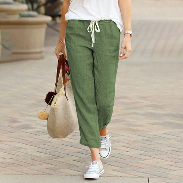 Woman wearing flared drawcord-waist pants with sneakers, walking through town.