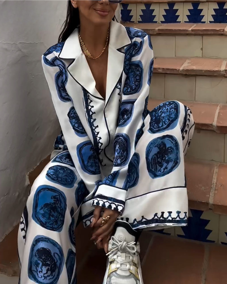 A woman wearing a blue-and-white printed open-collar shirt and matching straight-leg pants on a warm summer day