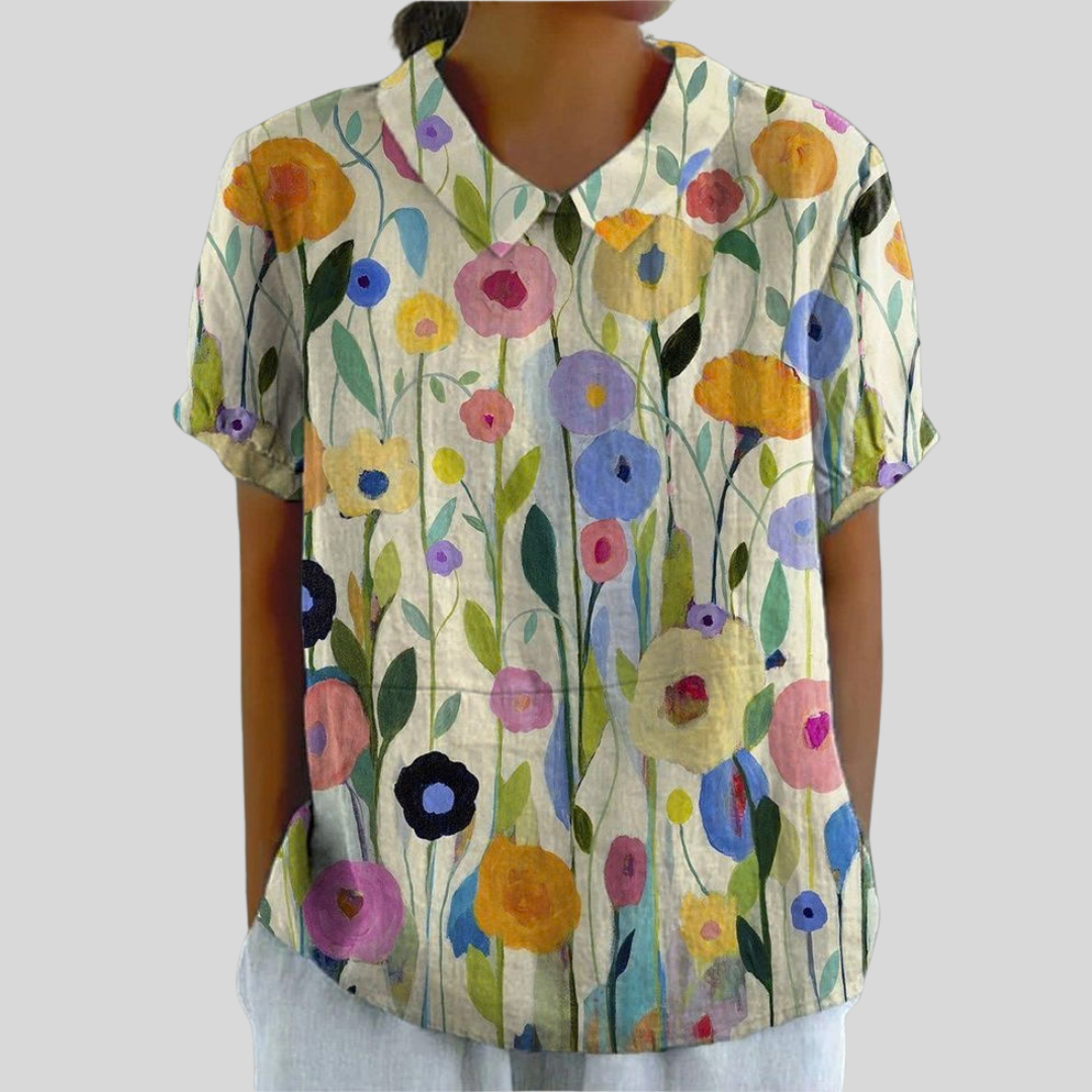 A woman in a blossom-print top with an elegant collar, dressed with easy confidence.