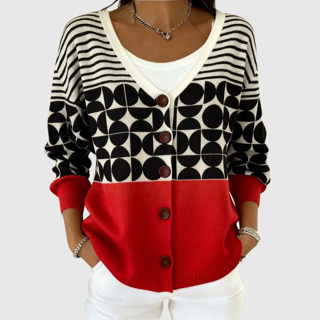 A woman wearing a black, cream and red colour-block cardigan with a bold geometric pattern.