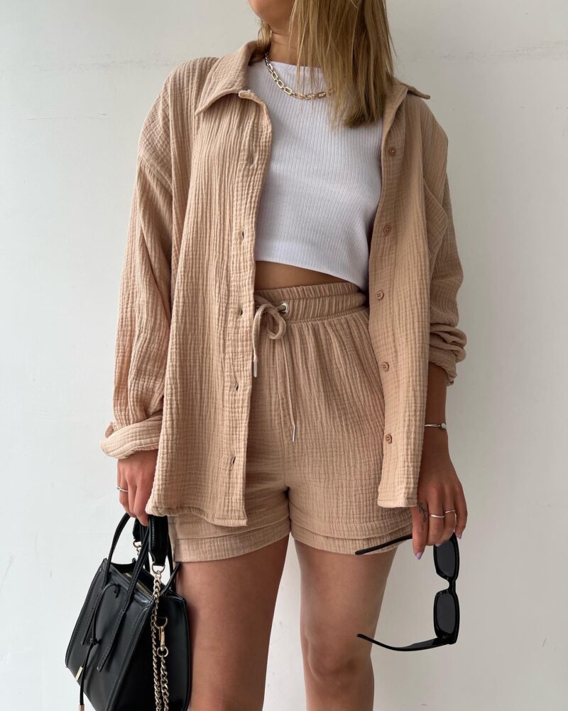 A woman wearing a relaxed button shirt with matching drawstring shorts, fresh and easy.