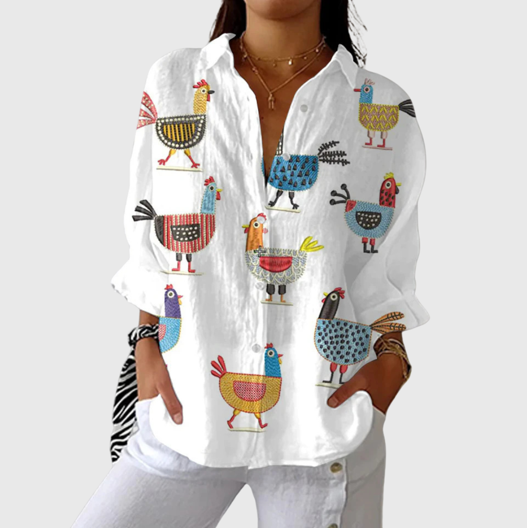 A woman wearing a loose colourful printed blouse with adjustable sleeves, styled with pants for a comfortable day out.