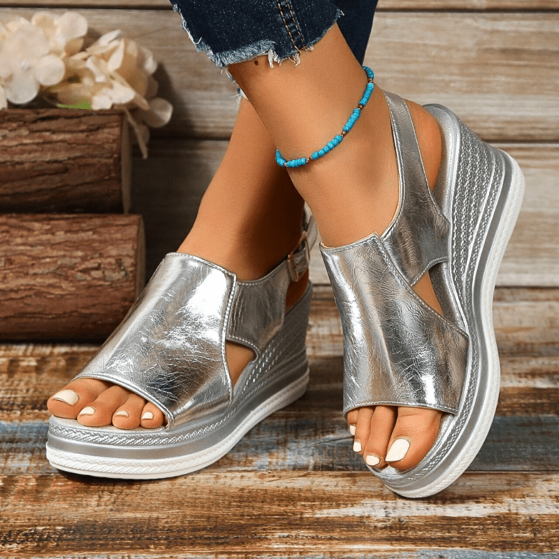 A woman wearing gold metallic sandals with a cushioned insole and wide, supportive fit.