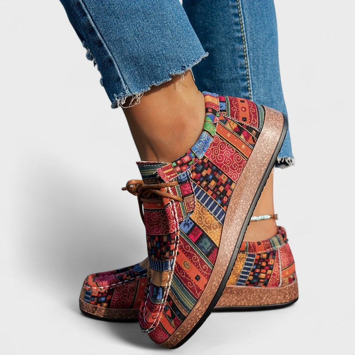 A woman wearing red boho-patterned lightweight sneakers on a walk in town.