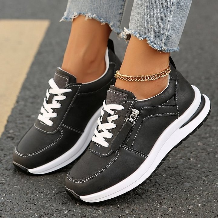 A woman wearing cushioned orthopaedic sneakers with a side zip