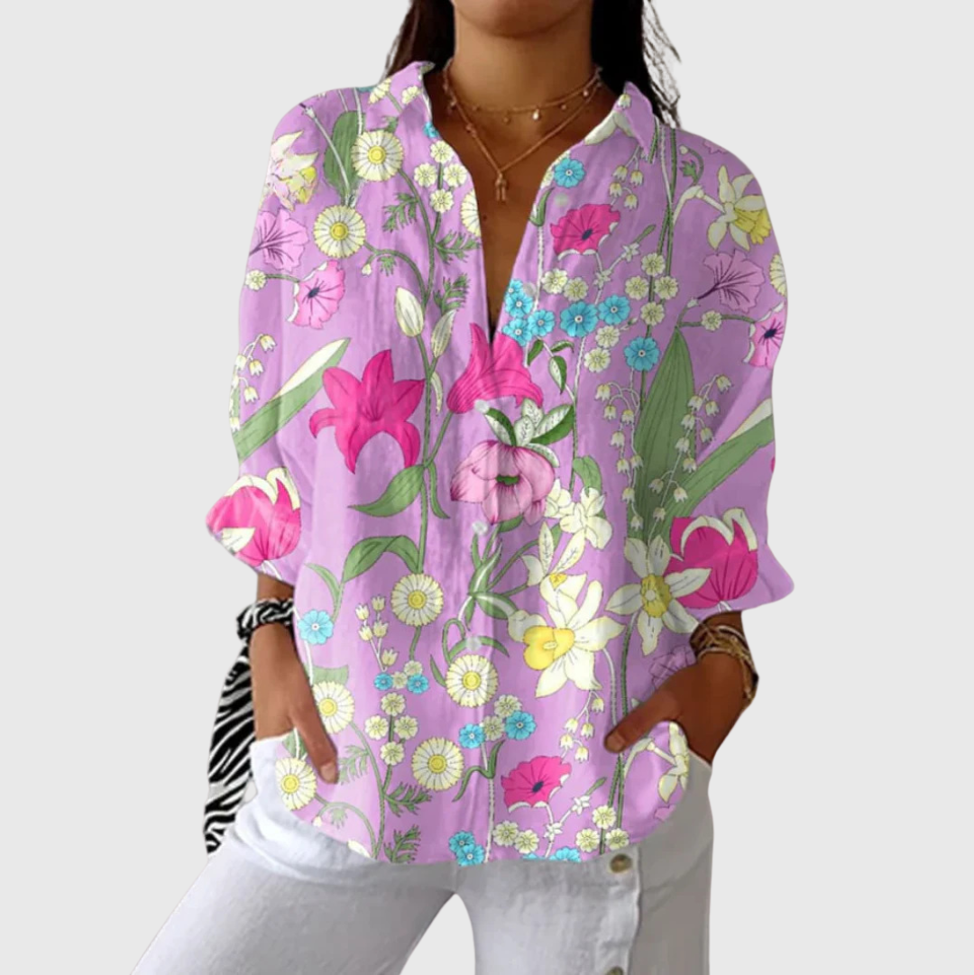 A woman wearing a relaxed colourful printed blouse with adjustable sleeves, styled with a skirt for a comfortable day out.