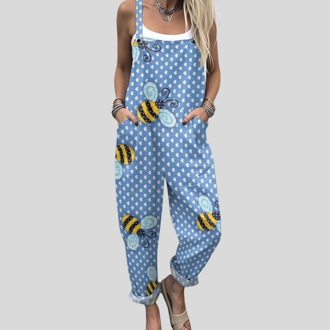 A woman wearing light blue overalls printed with cheerful little bees and fine dots, with adjustable straps.