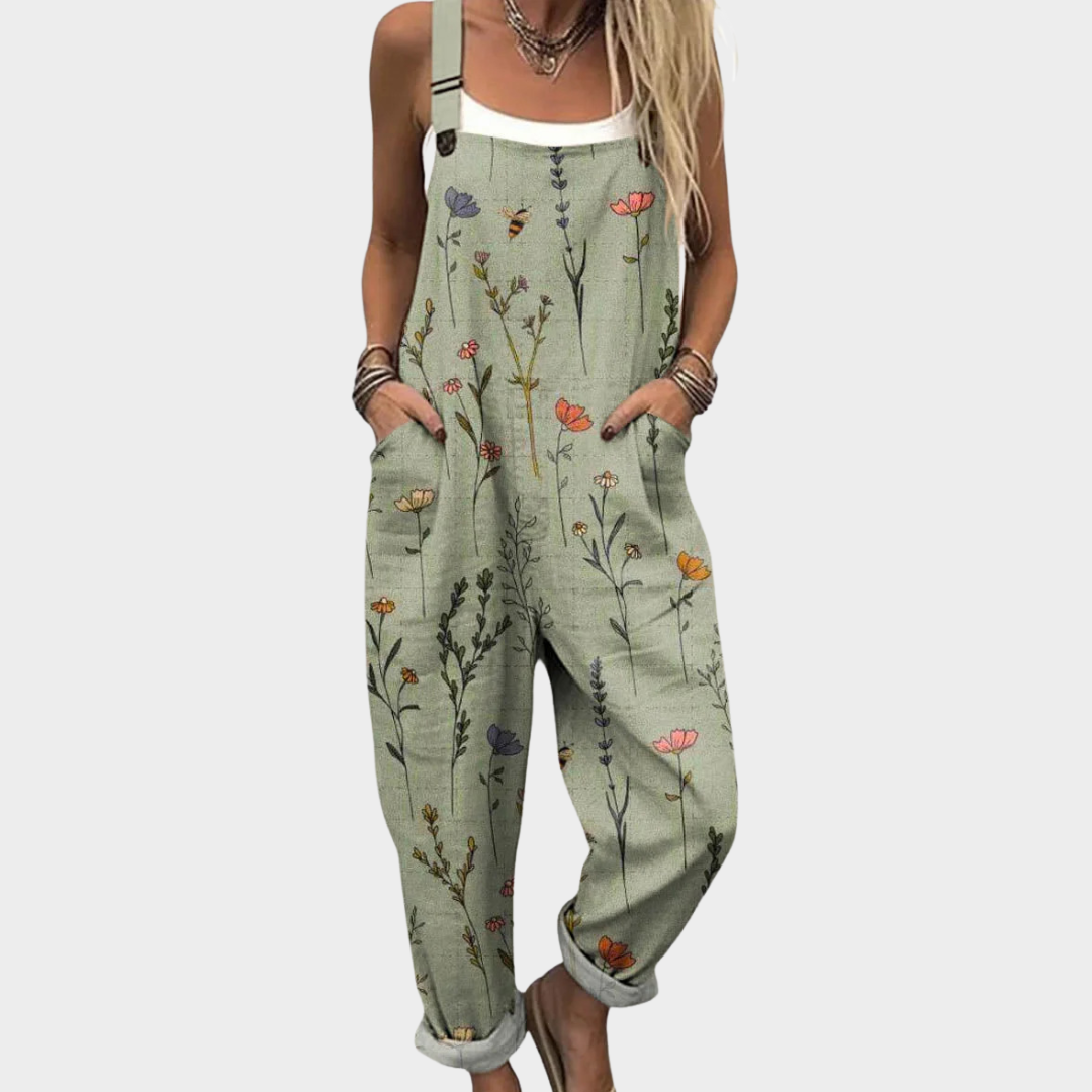 A woman wearing soft sage green overalls scattered with delicate wildflowers, with adjustable straps.