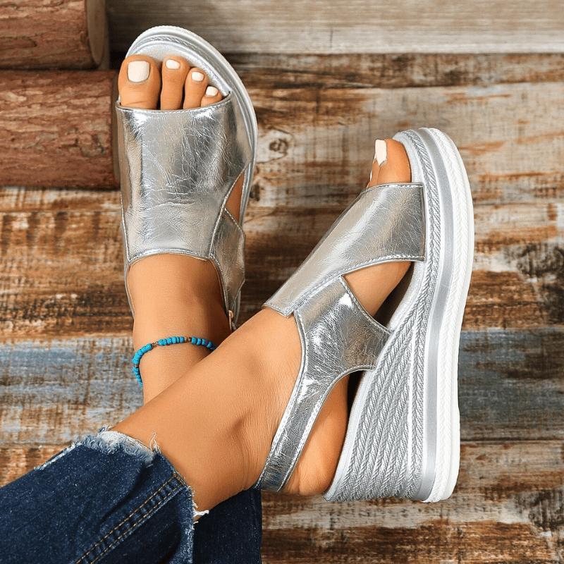 A woman wearing gold metallic sandals with a cushioned insole and wide, supportive fit.