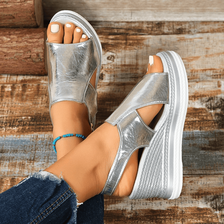 A woman wearing gold metallic sandals with a cushioned insole and wide, supportive fit.