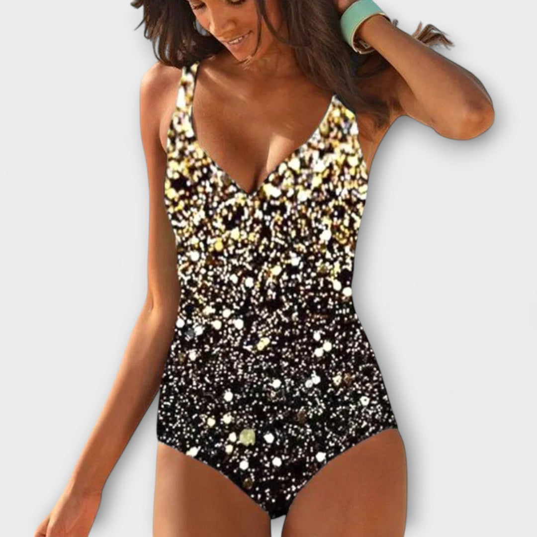 A woman by the pool in a black wrap-front one-piece swimsuit, relaxed and confident in the sun.