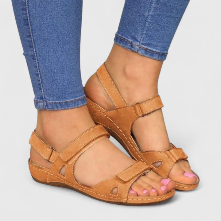 A woman walking through town in tan flat comfort sandals, relaxed and at ease.