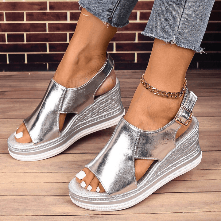 A woman wearing gold metallic sandals with a cushioned insole and wide, supportive fit.