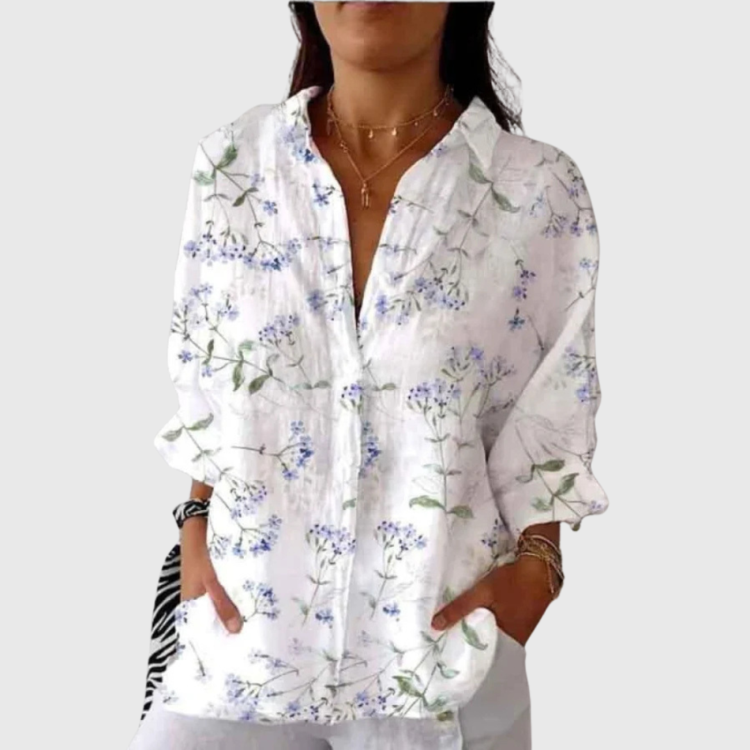 A woman wearing a colourful floral printed blouse, relaxed and smiling outdoors