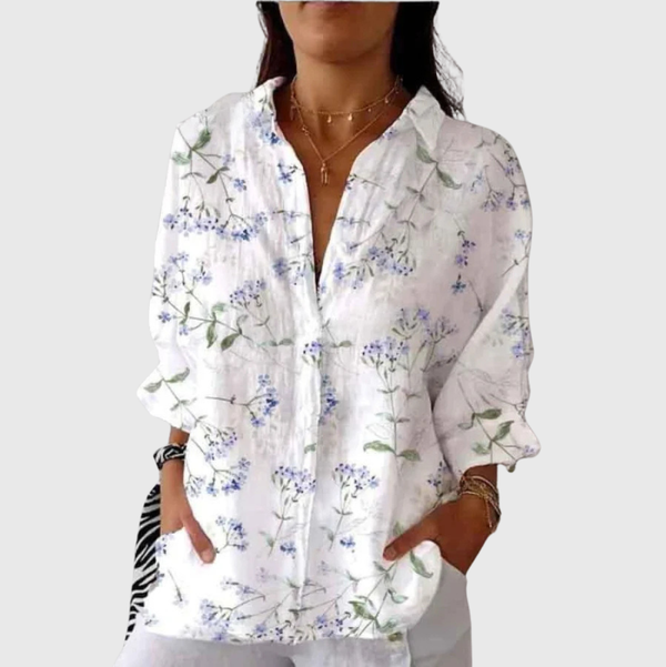 A woman wearing a colourful floral printed blouse, relaxed and smiling outdoors