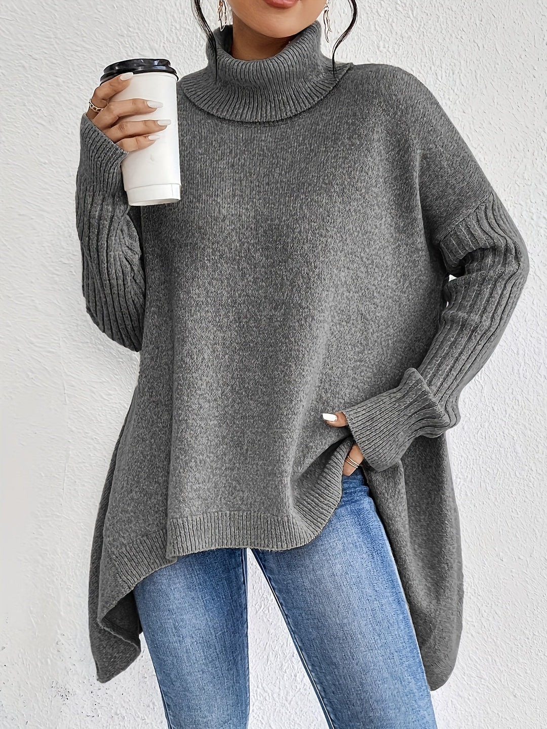 A woman wearing a stand-collar sweater with a chic asymmetric drape, warm and polished.