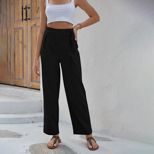 Woman wearing high-waisted wide-leg pants with a knot detail and a tucked-in top.